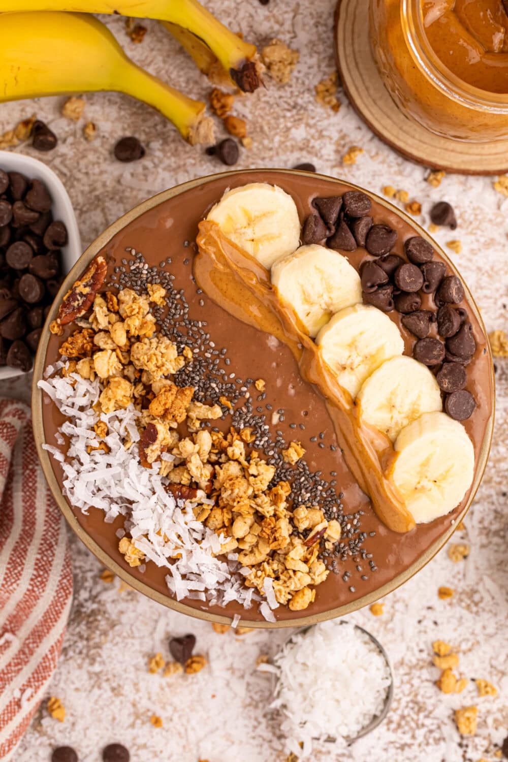 Peanut butter banana chocolate smoothie bowl topped with coconut, granola, chips, and bananas. 