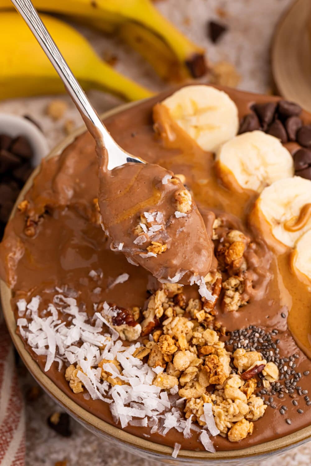 Spoon full of chocolate peanut butter banana smoothie with toppings. 