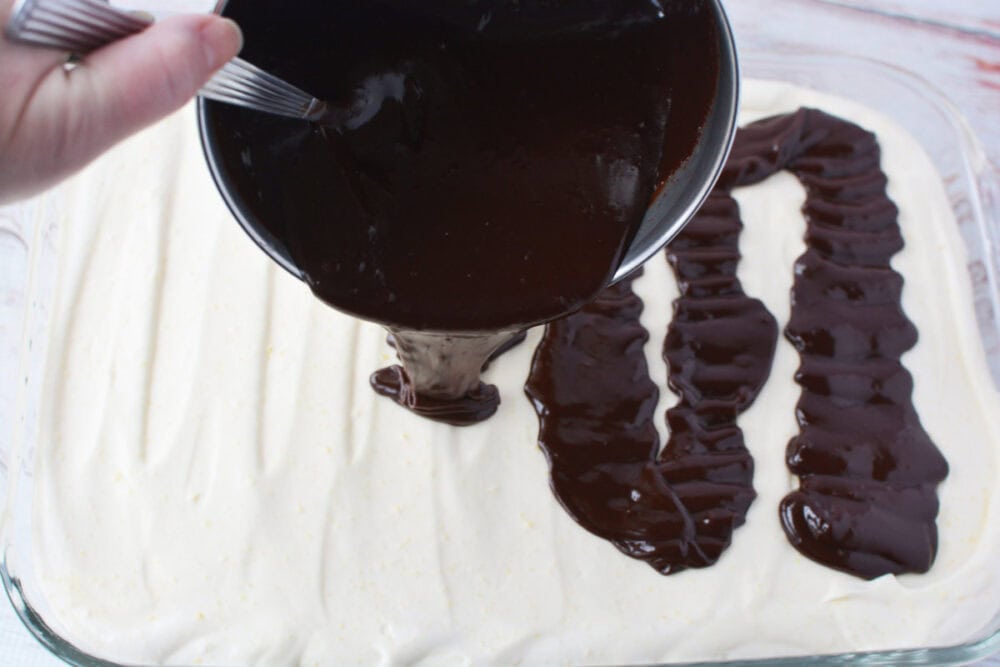 Pouring chocolate ganache onto eclair cake