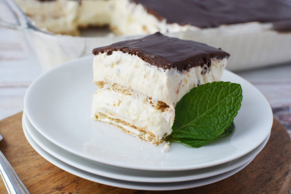 Layered chocolate ice box cake on a plate topped with chocolate ganache. 