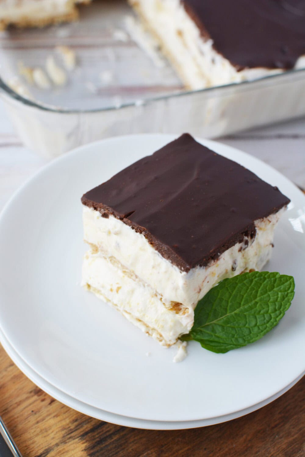 Chocolate eclair cake on a plate with a mint leaf. 