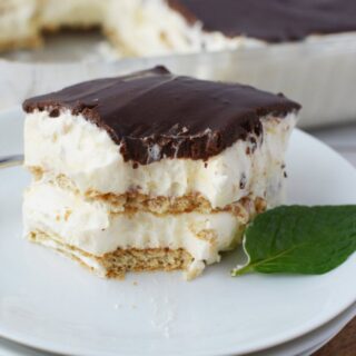 Chocolate eclair cake on a white plate with a bite taken out.