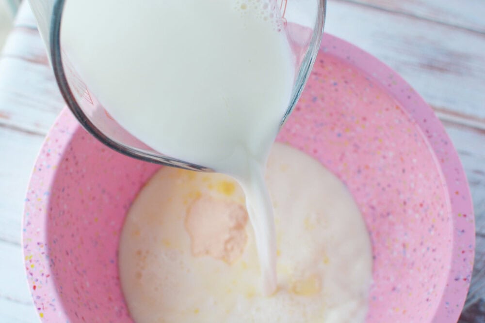 Pouring milk into mixing bowl with pudding mix.