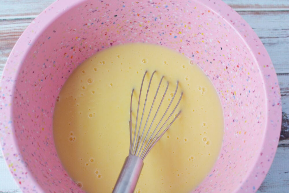 Whisking pudding in a pink mixing bow.