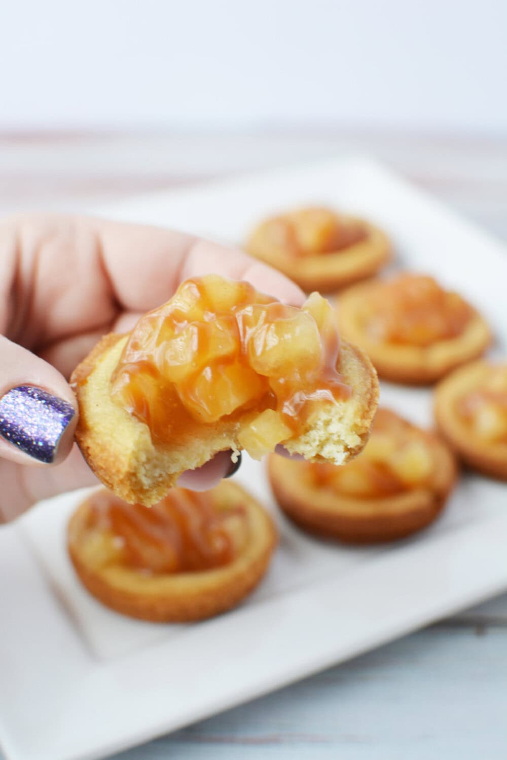 Holding a caramel apple pie cookie with a bite missing. 