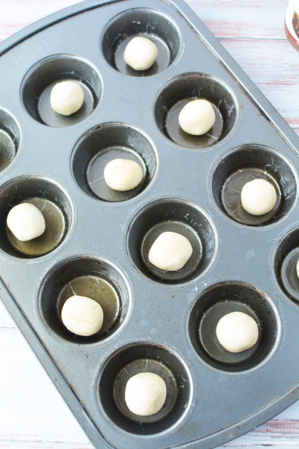 Balls of cookie dough in a muffin tin. 