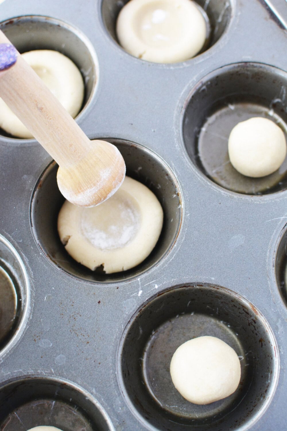 Using a tart shaper on dough in muffin tins. 