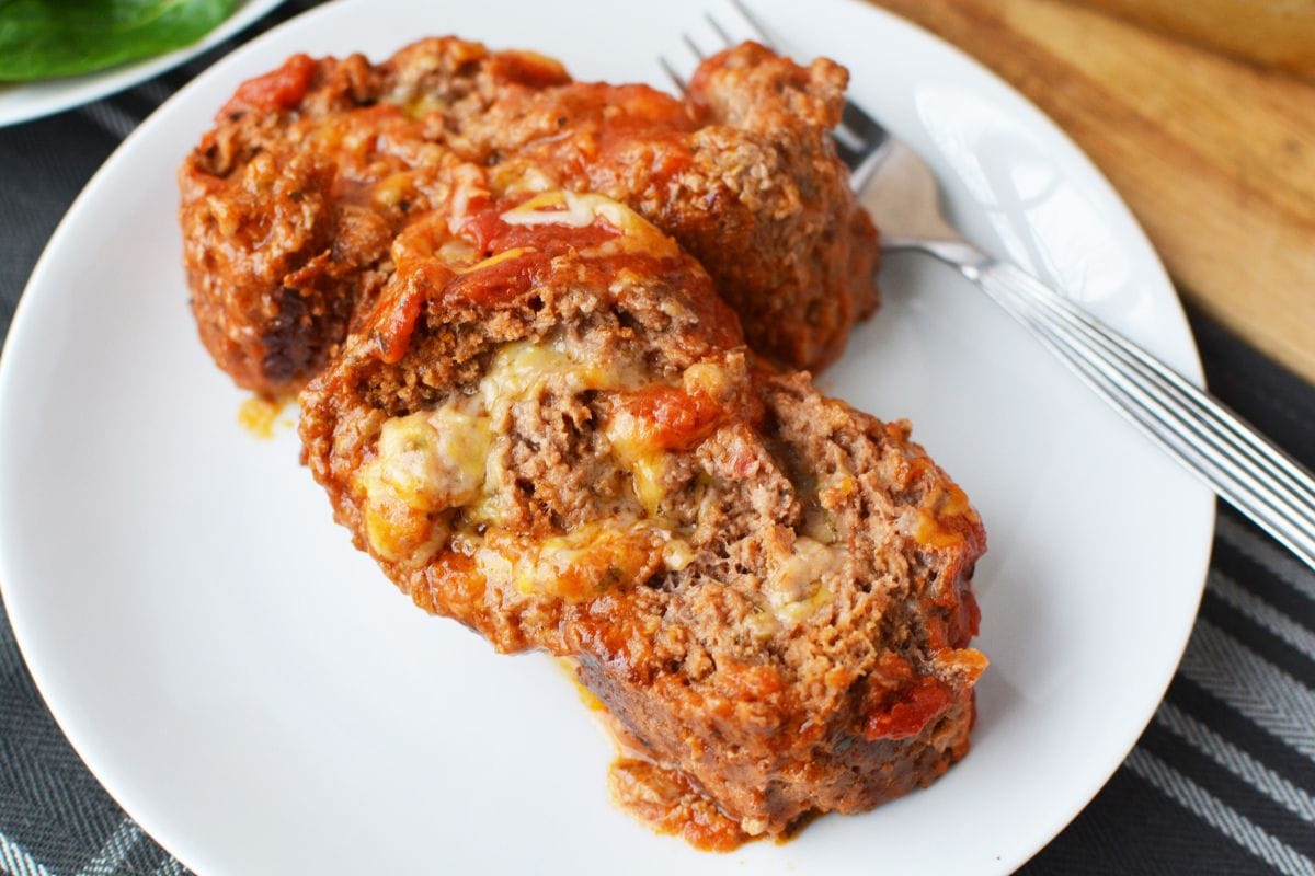 Slice of cheese stuffed meatloaf on a plate. 