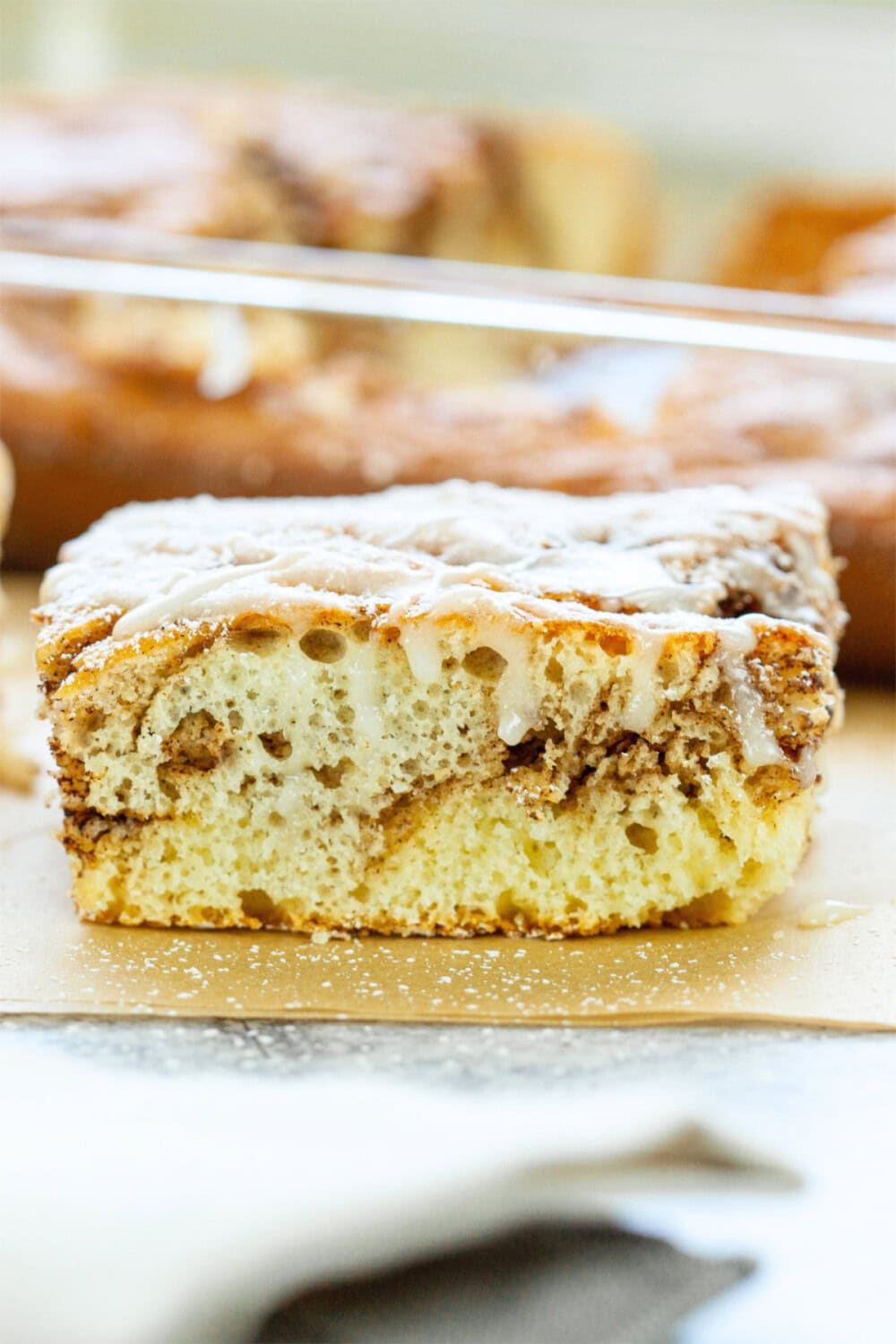 Slice of cinnamon roll cake on parchment paper sheets. 