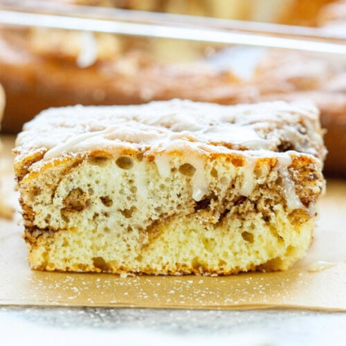 Slice of cinnamon roll cake on parchment paper sheets.