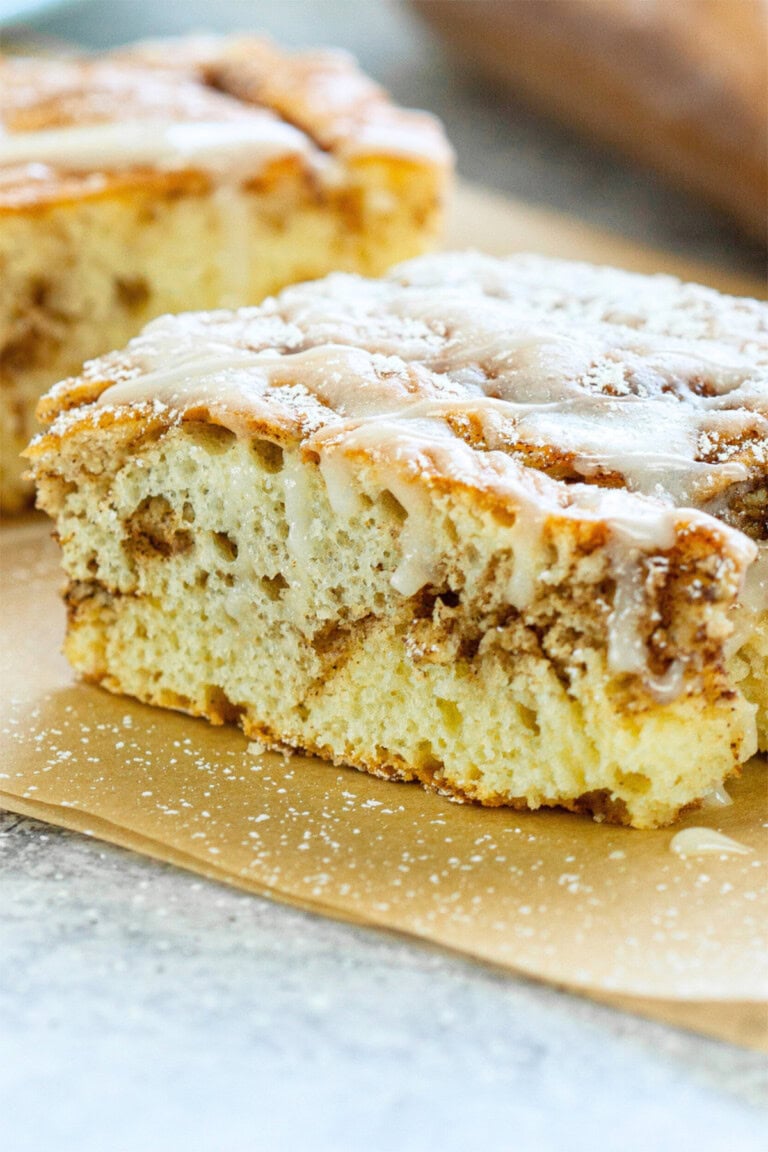 Cinnamon roll cake sliced on parchment paper.