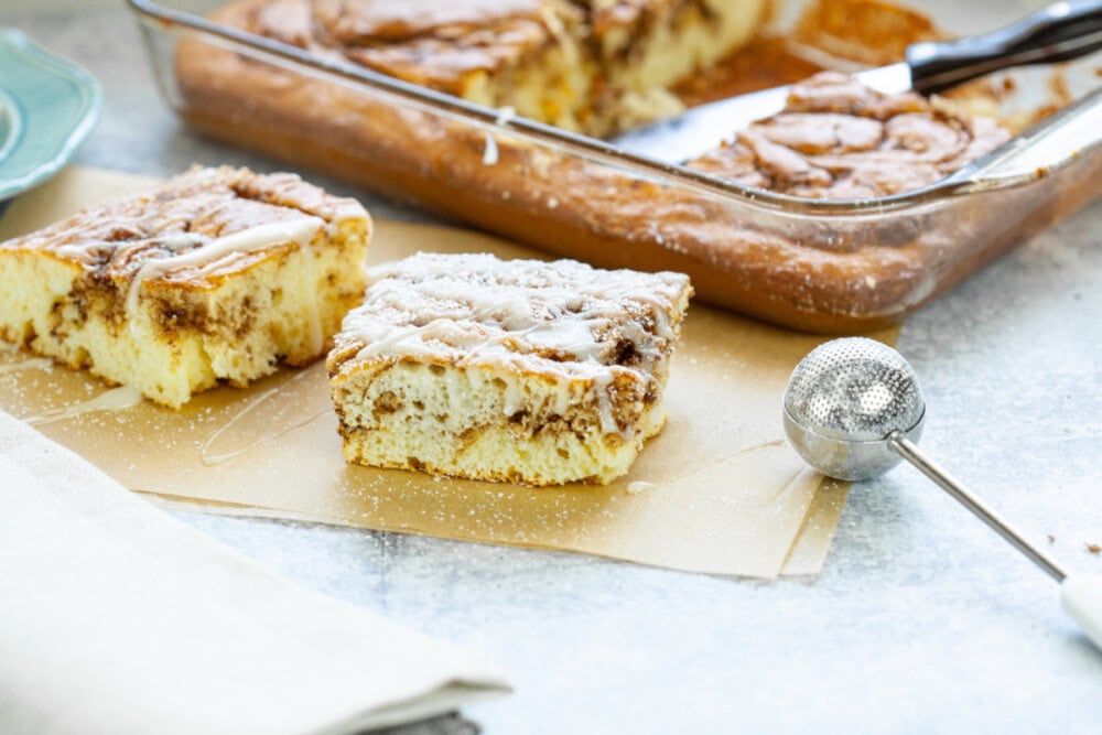 Slice of cinnamon roll cake next to baking pan. 