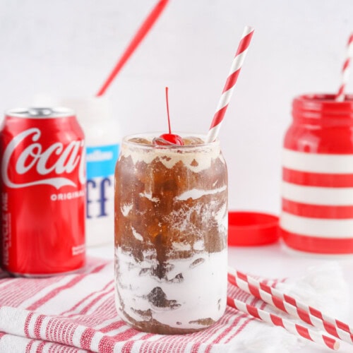 Glass of Fluffy Coke, can of Coca-Cola Classic, straws, and cherries.