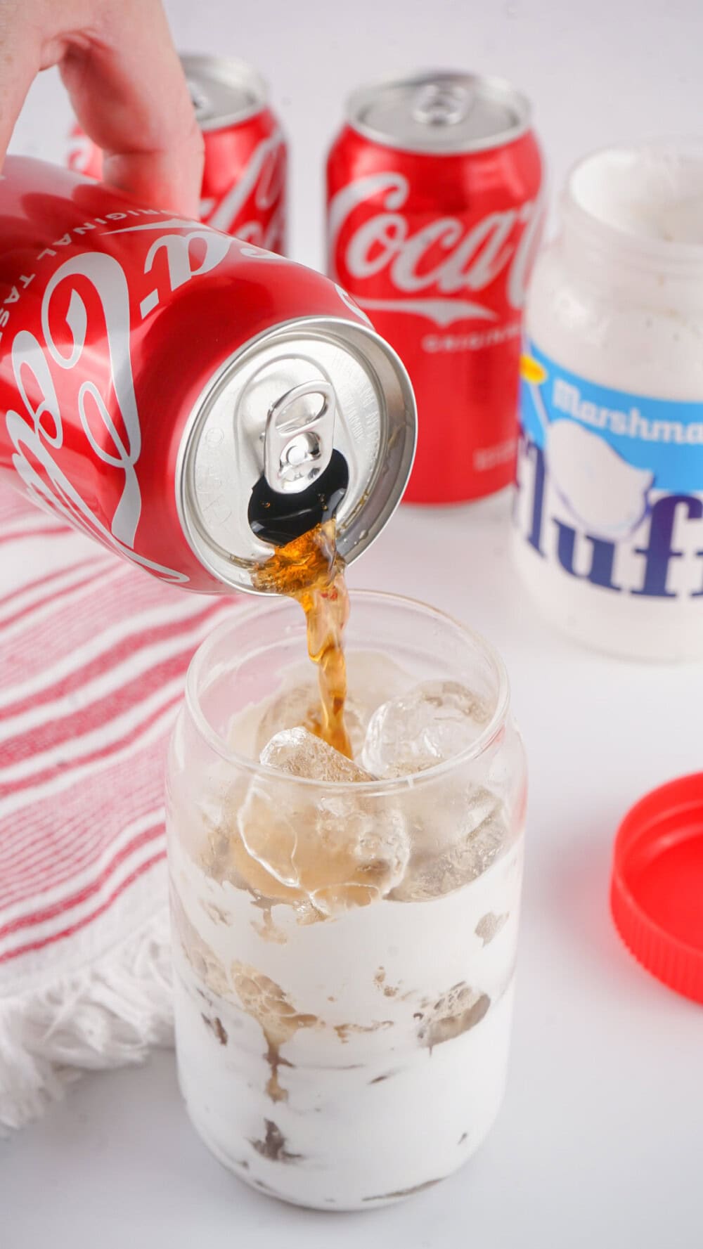 Pouring Coca-Cola Classic into a jar with fluff and ice. 