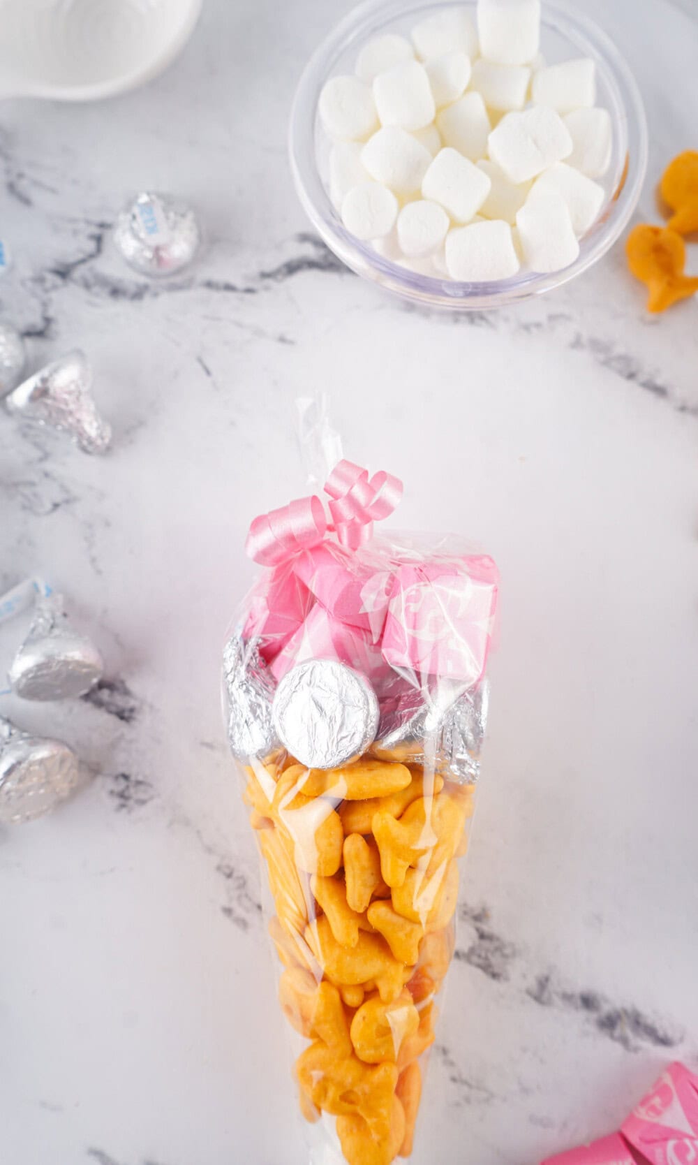 Tying ribbon onto treat bag that looks like a pencil. 