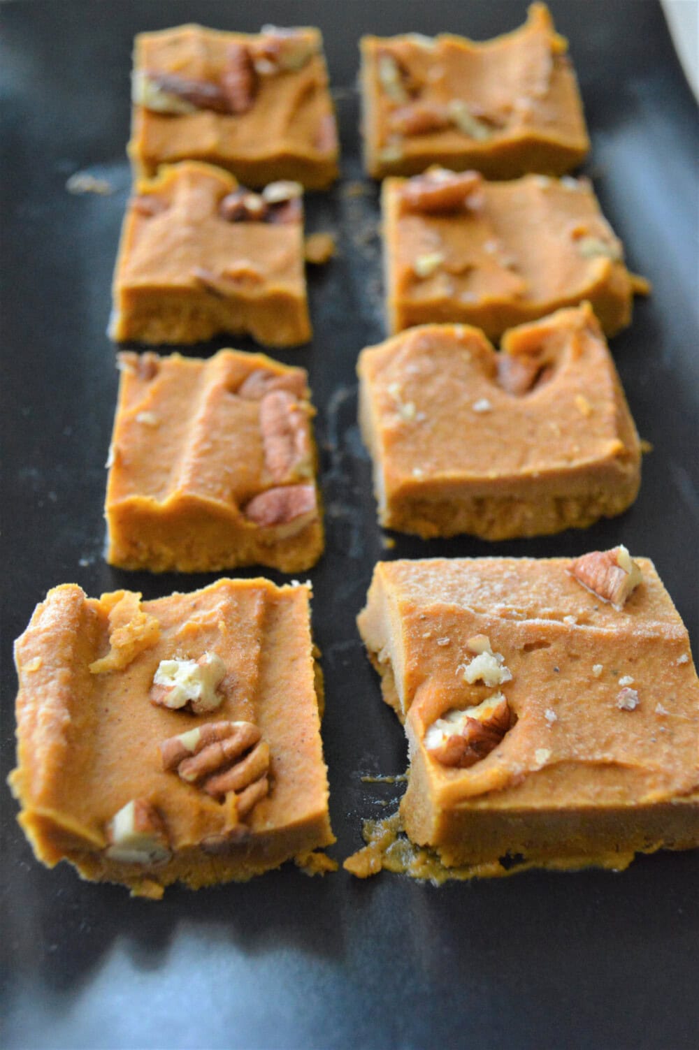 Pumpkin peanut butter fudge lined up on a board. 