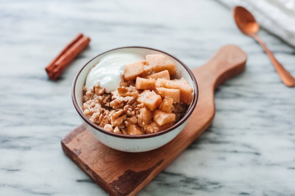 Bowl of quinoa topped with apples and yogurt. 