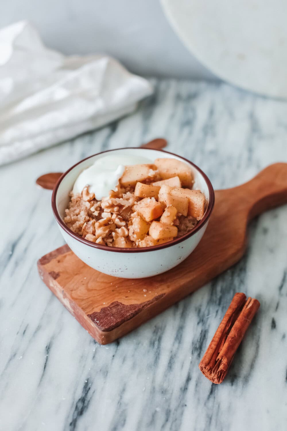 Bowl of quinoa and apples topped with cinnamon and yogurt.