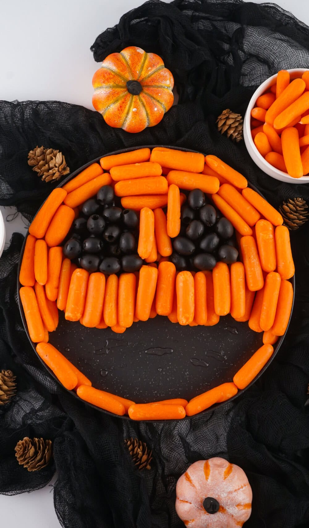 Arranging baby carrots and olives on a round platter. 