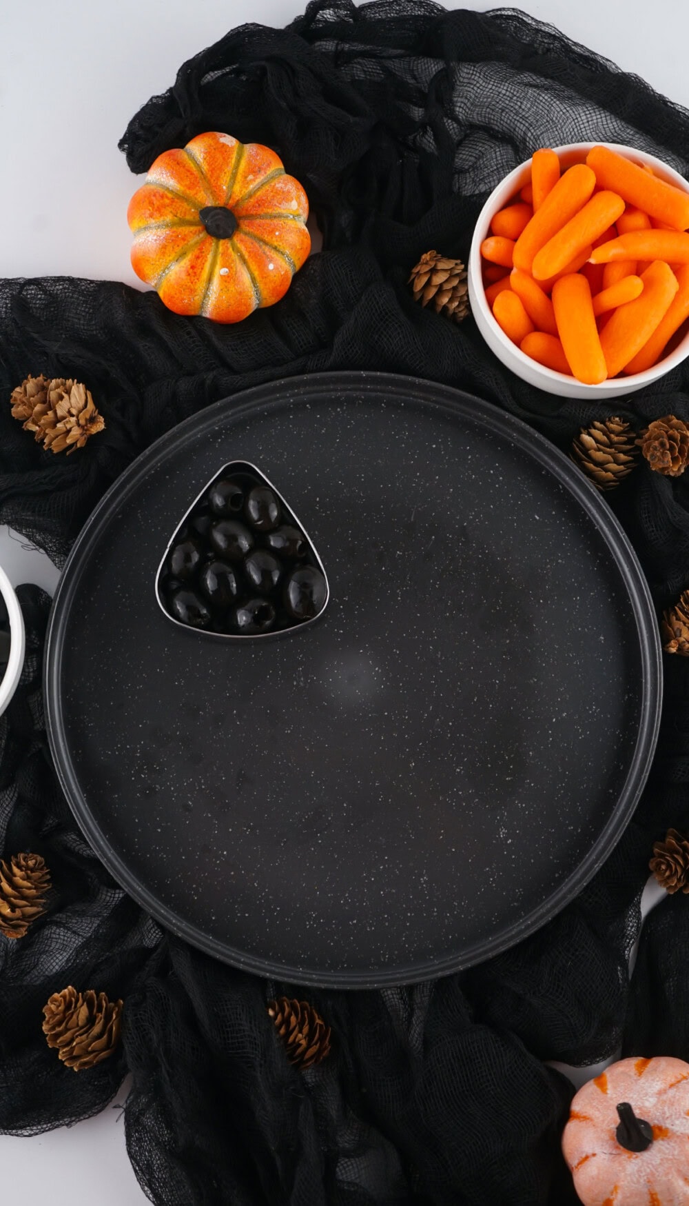 Triangle of olives on a black platter. 