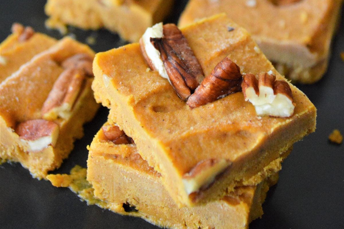 Slices of pumpkin peanut butter fudge topped with nuts. 