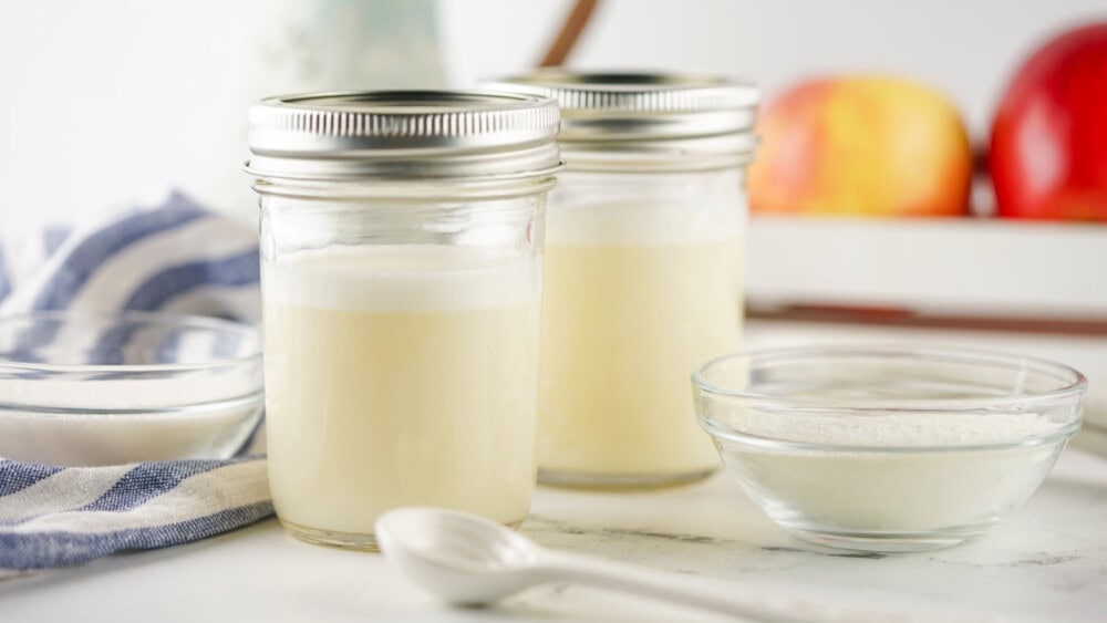 Two mason jars with homemade sweetened condensed milk in them. 