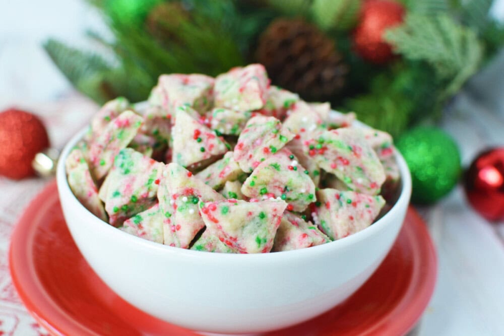 Mini shortbread cookies with Christmas non pareils in a bowl.