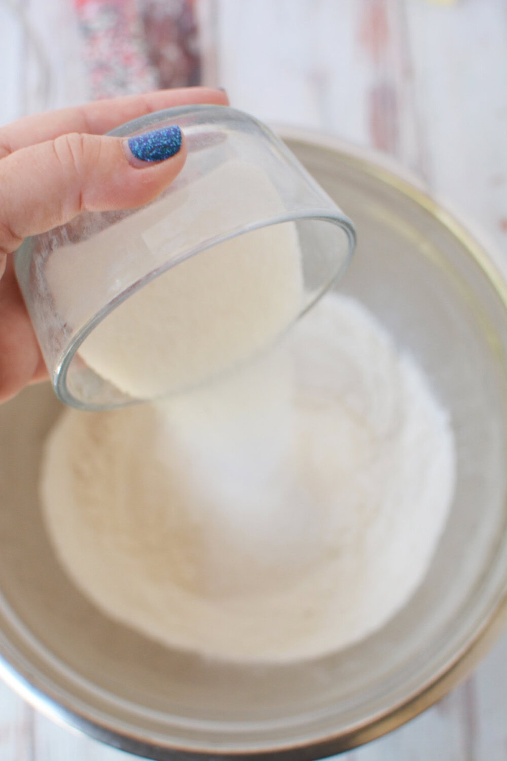 Pouring sugar into flour in a mixing bowl. 