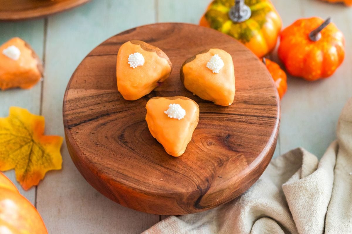 Pumpkin caked bites shaped like pie slices on a board. 