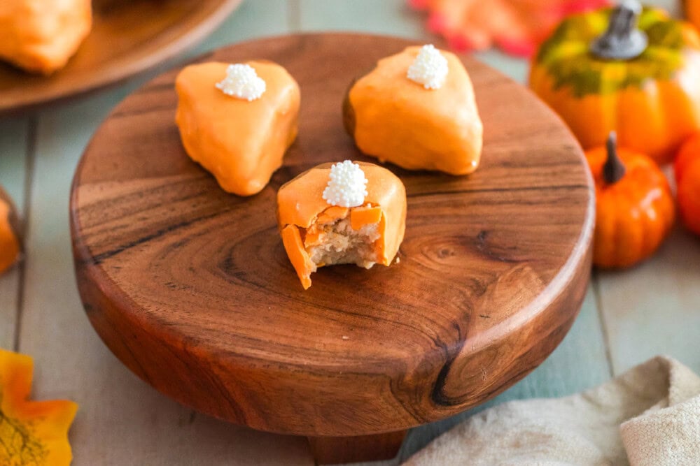 Pumpkin pie cake bites on a board with a bite missing from one. 