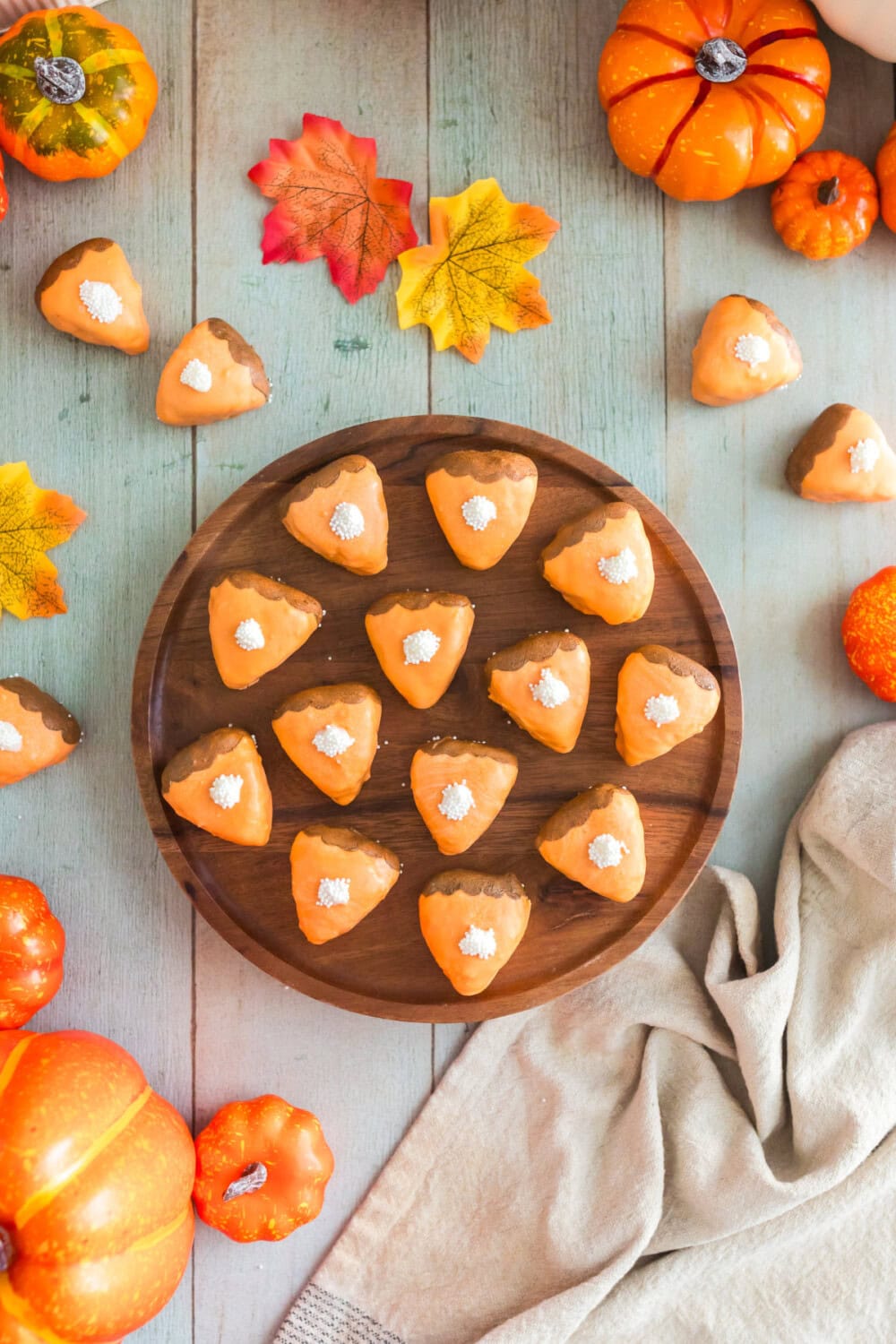 Cake bites that look like pumpkin pie slices on a board and on the table.