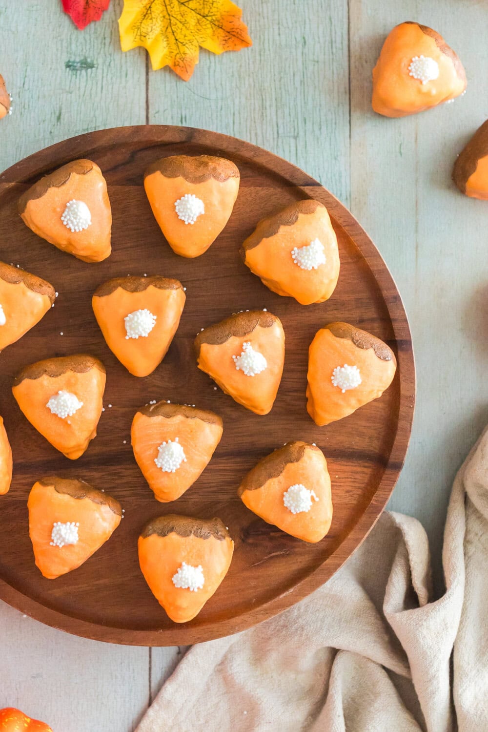 Several pumpkin pie cake bites on a round, wooden board.