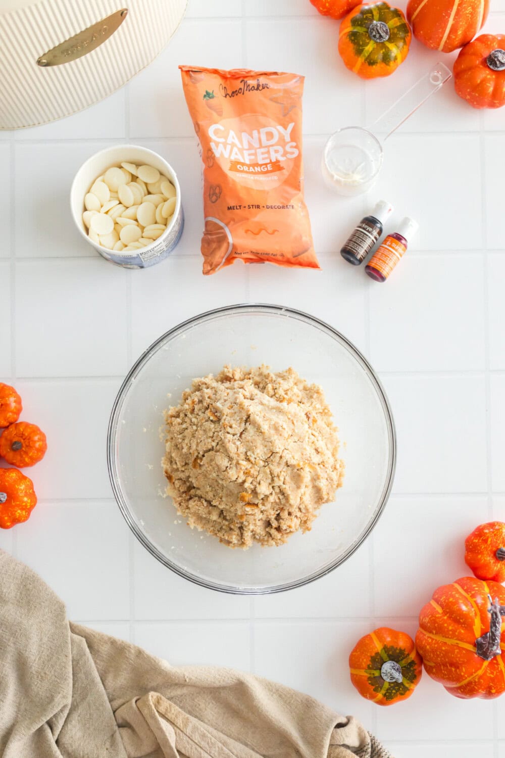 Cake mix, candy melts, food coloring, and fall decor on a table.