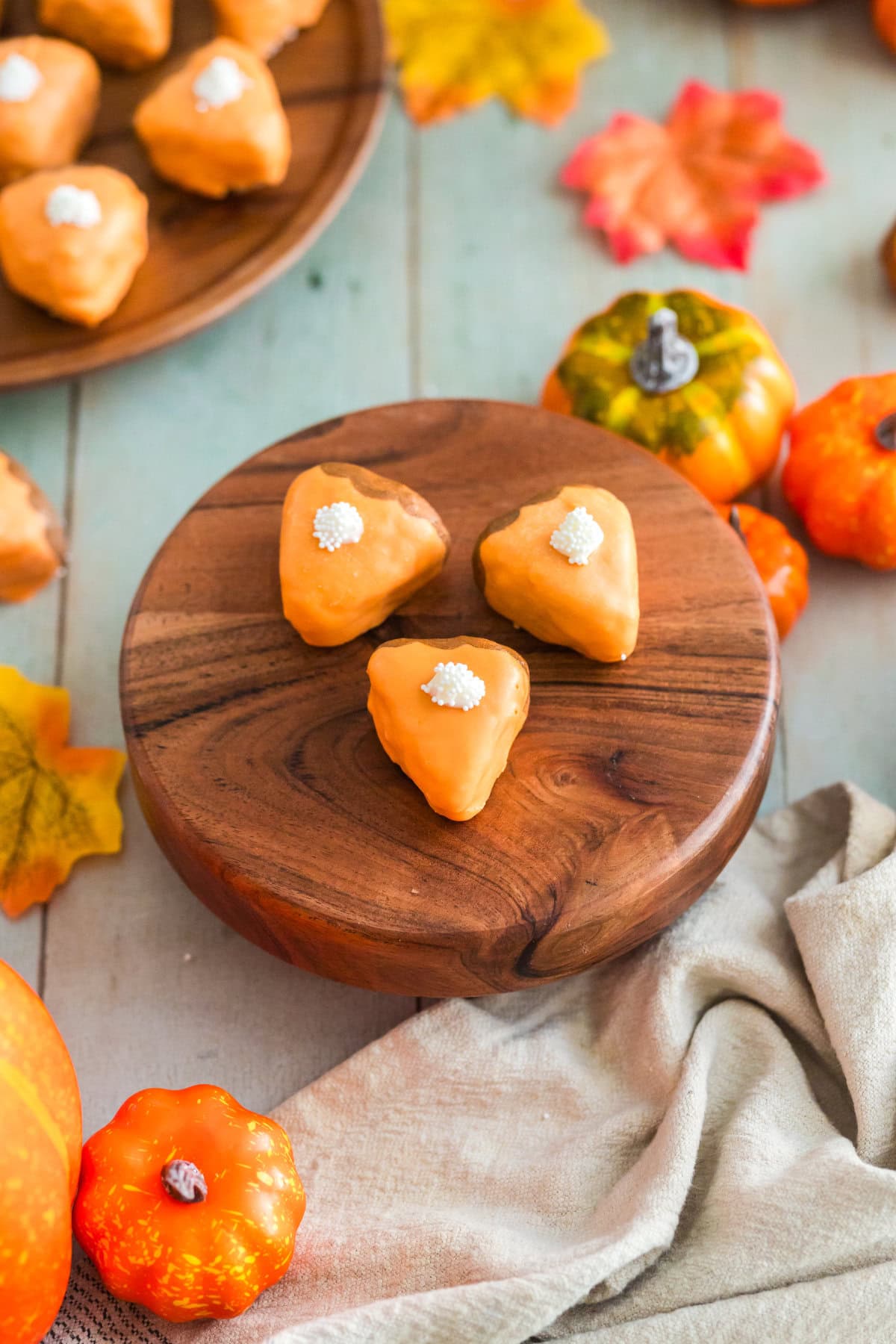 Pumpkin pie cake bites sitting on a board with fall decor on the table.