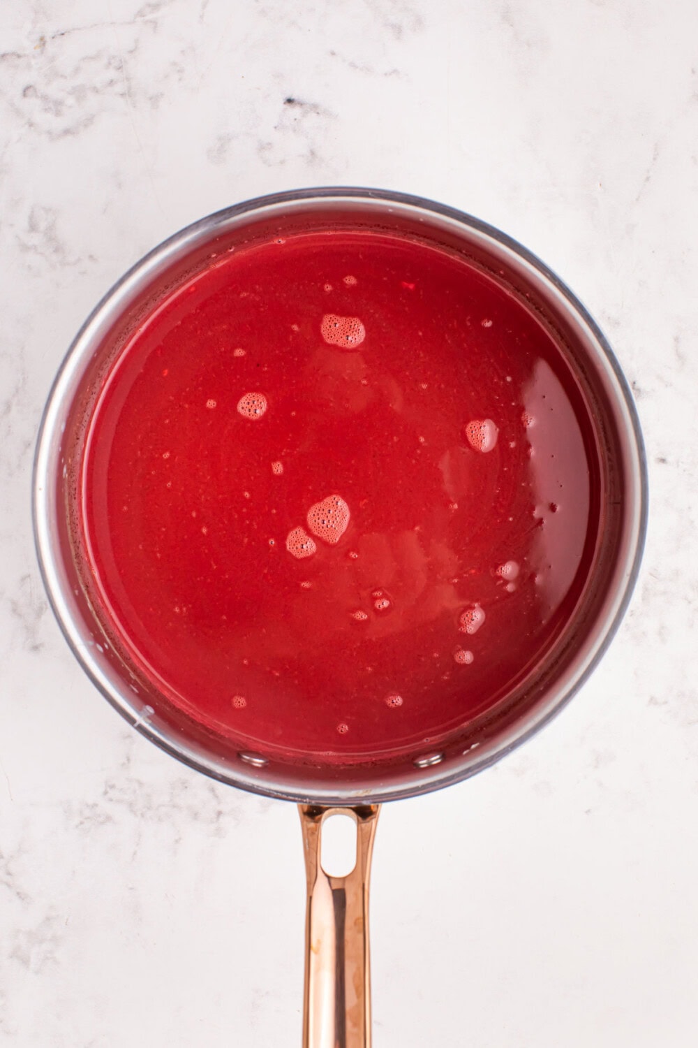 Red colored melted chocolate in a pan.