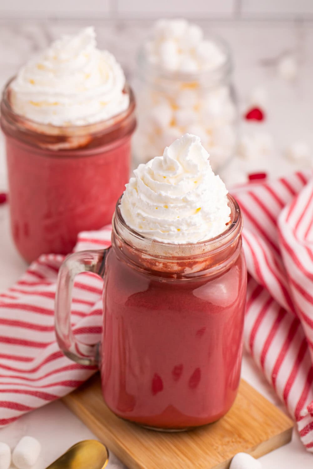 Jar full of red hot chocolate with whipped cream on top.