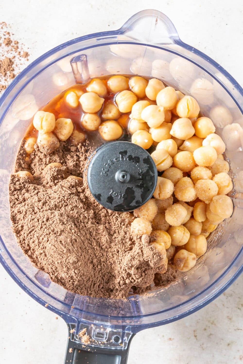 Chickpeas, cacao, and other ingredients in a food processor. 