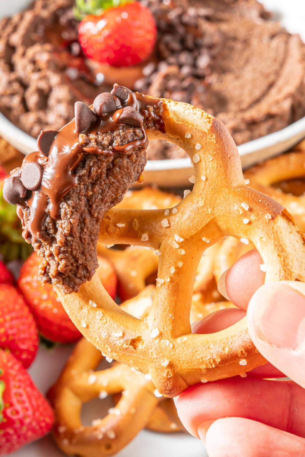 Dipping a pretzel into chocolate hummus. 