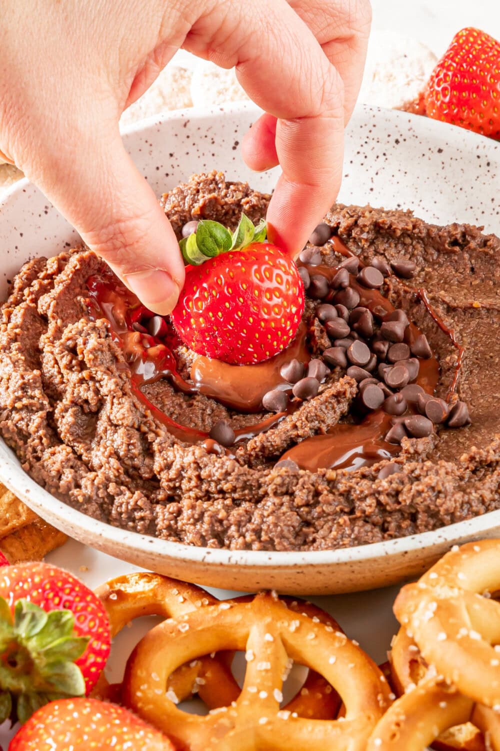 Dipping a strawberry into dark chocolate hummus. 