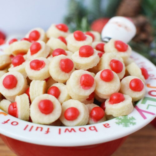 a bowl of shortbread bites with a red candy in the centers of them