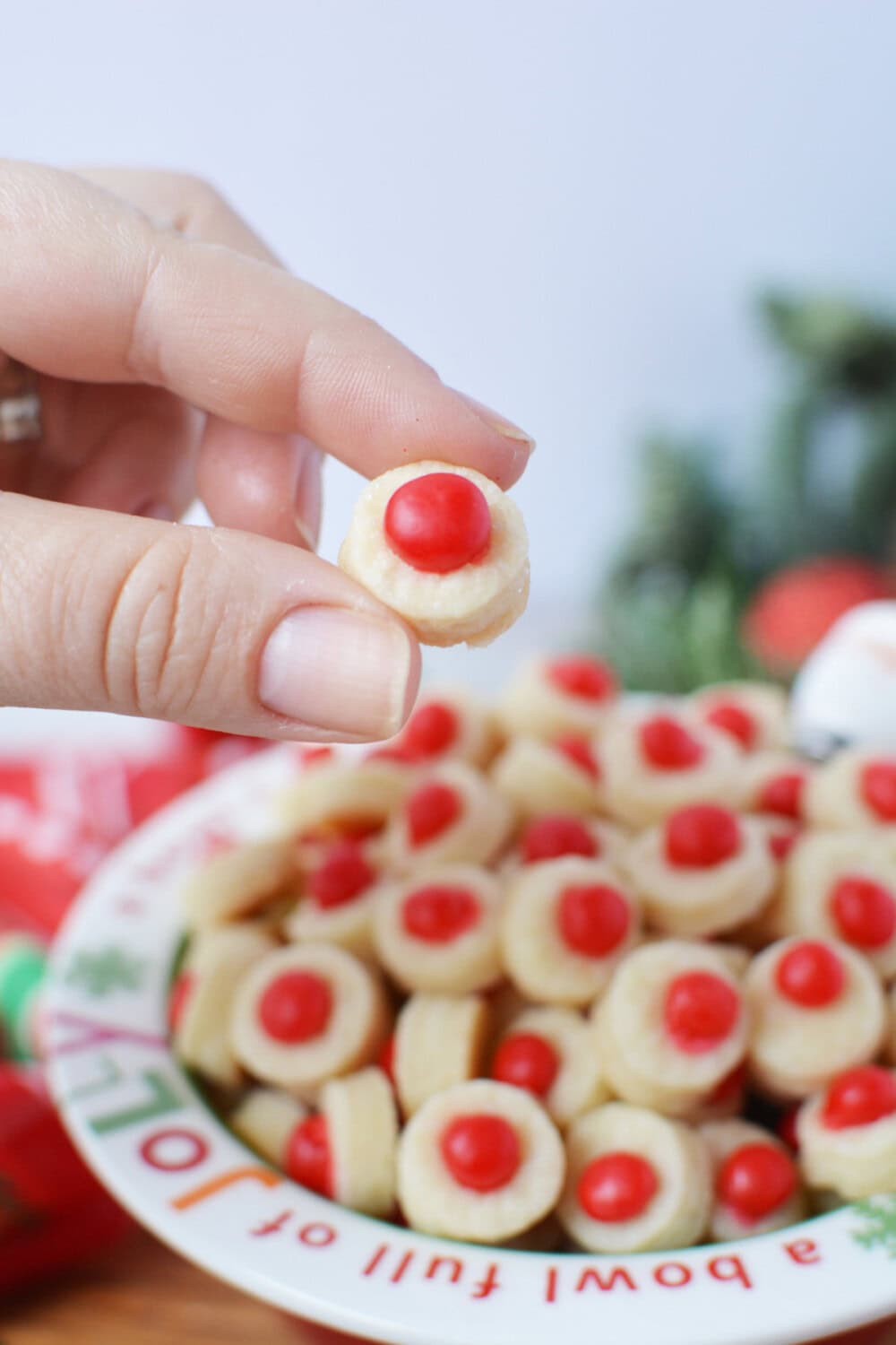 Hand holding a mini cookie with a red candy in the center