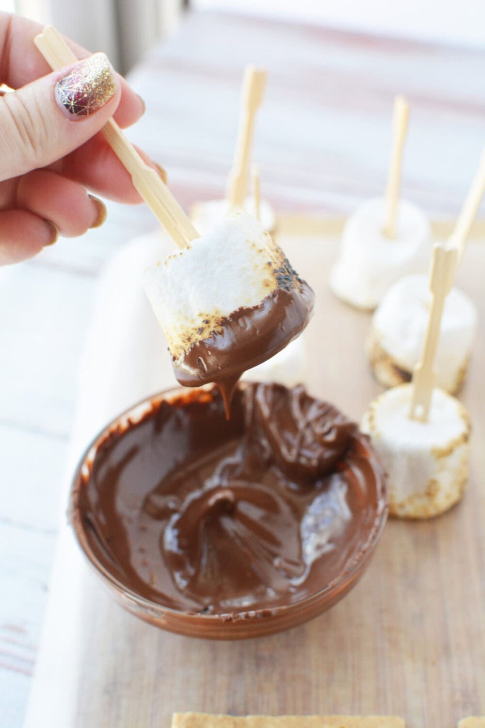 Dipping a marshmallow into melted chocolate. 