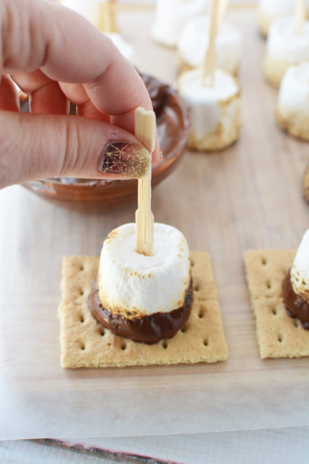 Pressing a chocolate dipped marshmallow onto a graham cracker