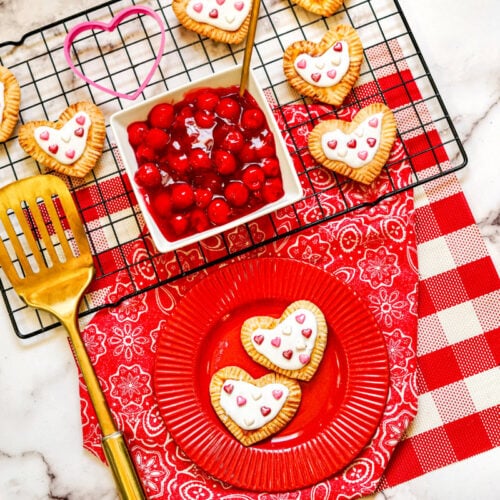 Heart-shaped toaster pastries on a red plate and a wire rack.