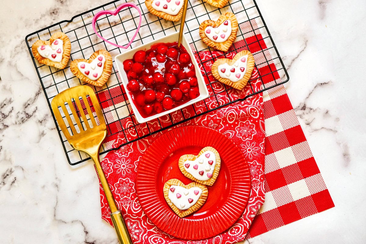 Heart-shaped toaster pastries on a red plate and a wire rack.