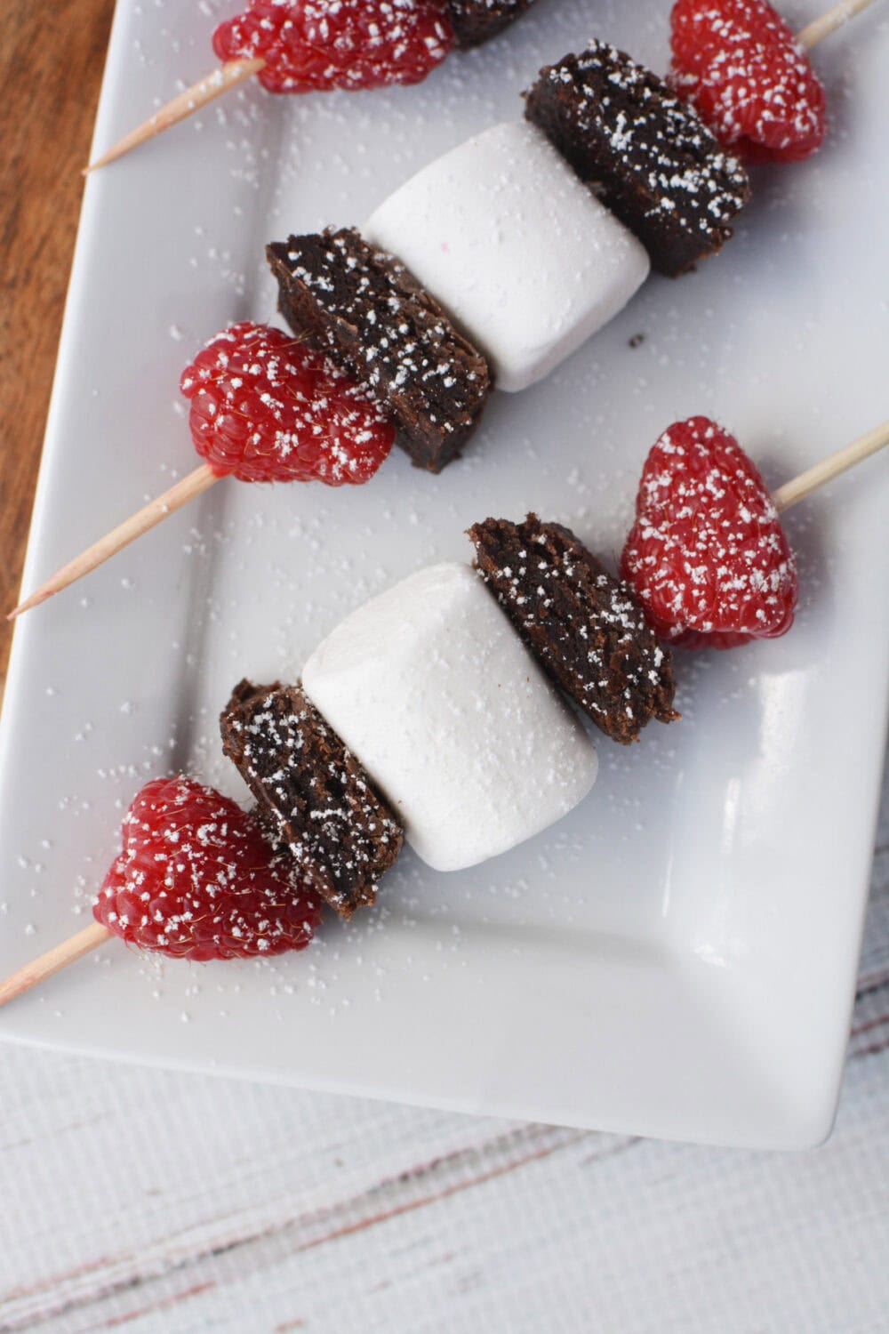 Brownie raspberry kabobs on a tray.