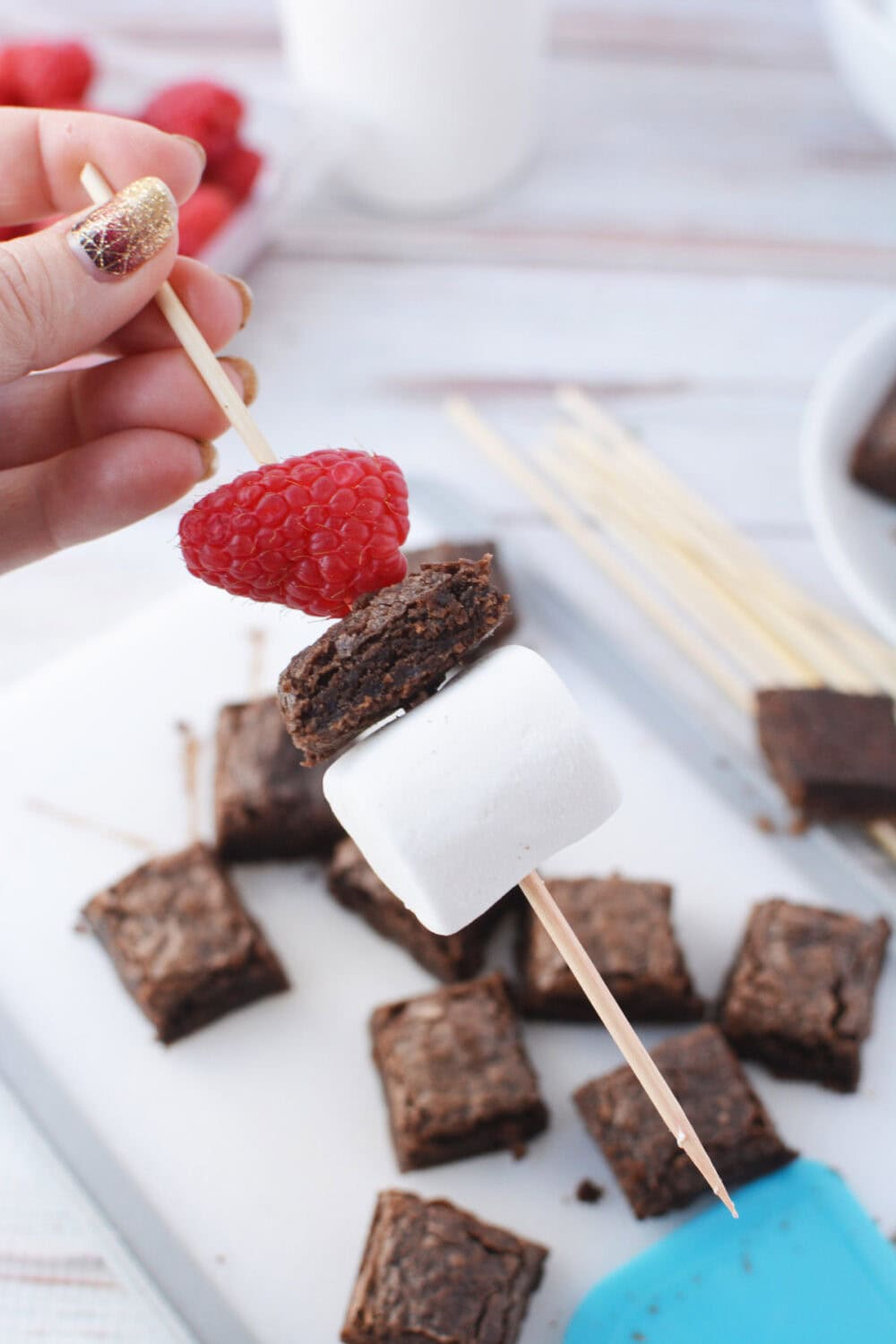 Marshmallow on a wooden stick with a brownie and a raspberry.