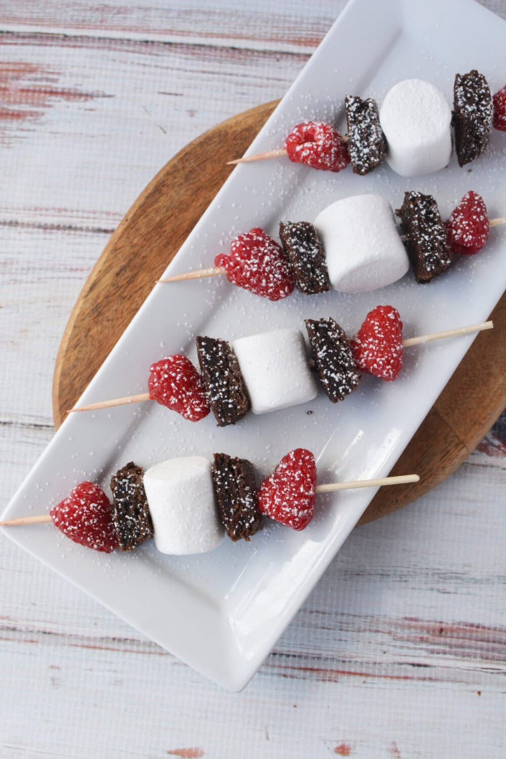 Brownie skewers dusted with powdered sugar on a serving tray.