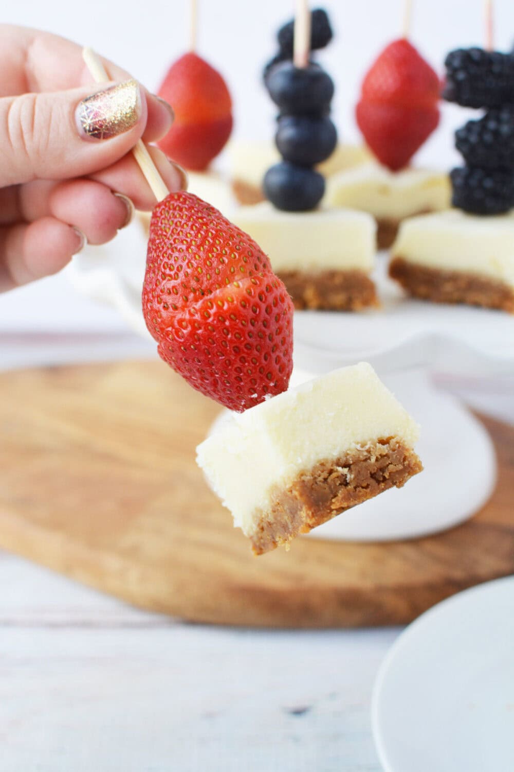 Strawberries pieces on a skewer with cheesecake.