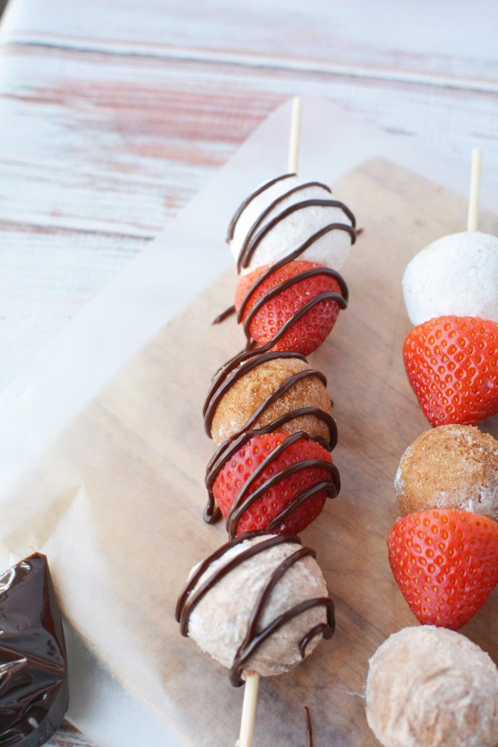 Chocolate drizzle over a donut hole kabob.